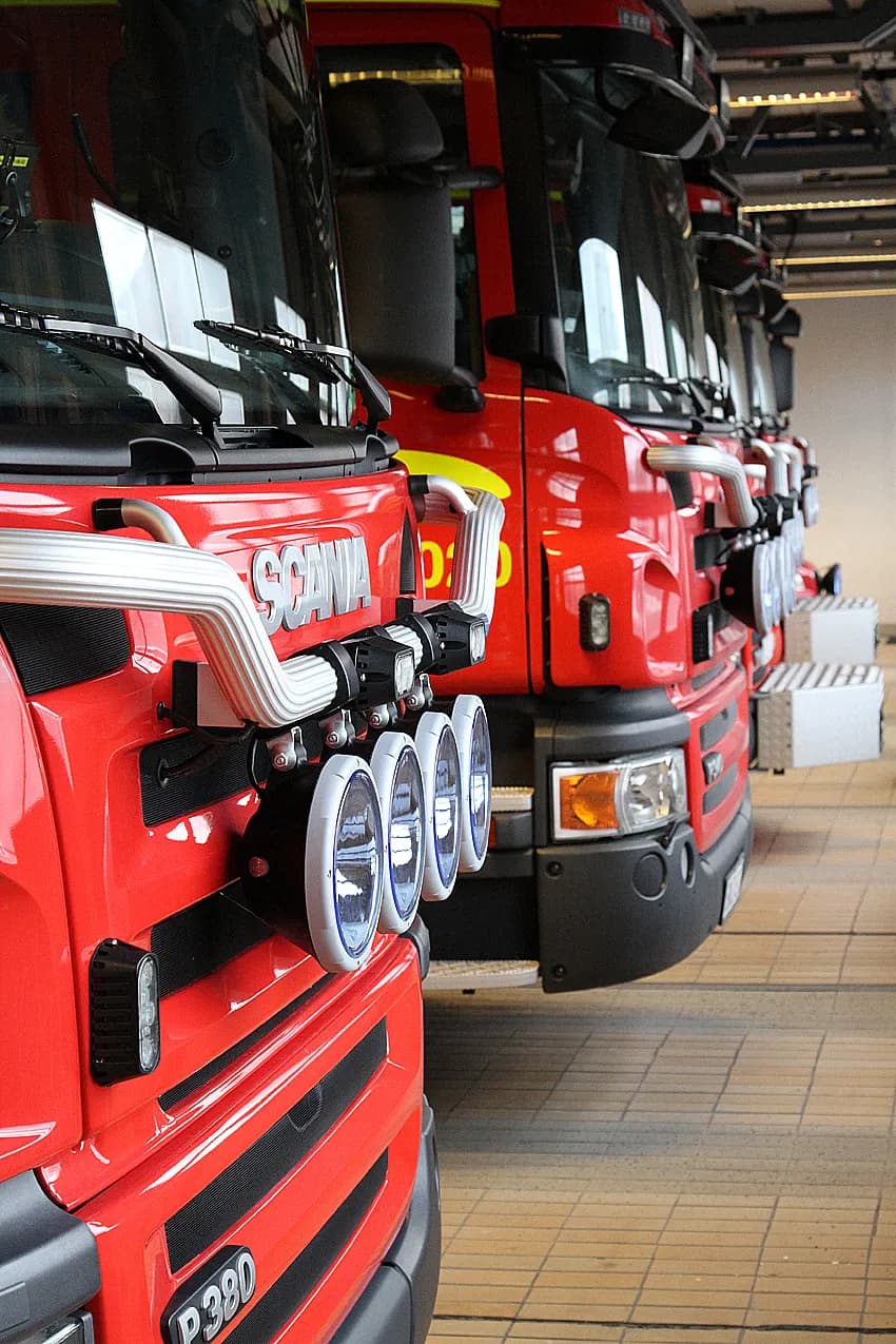 Row of red Scania fire trucks from the front in vehicle bay