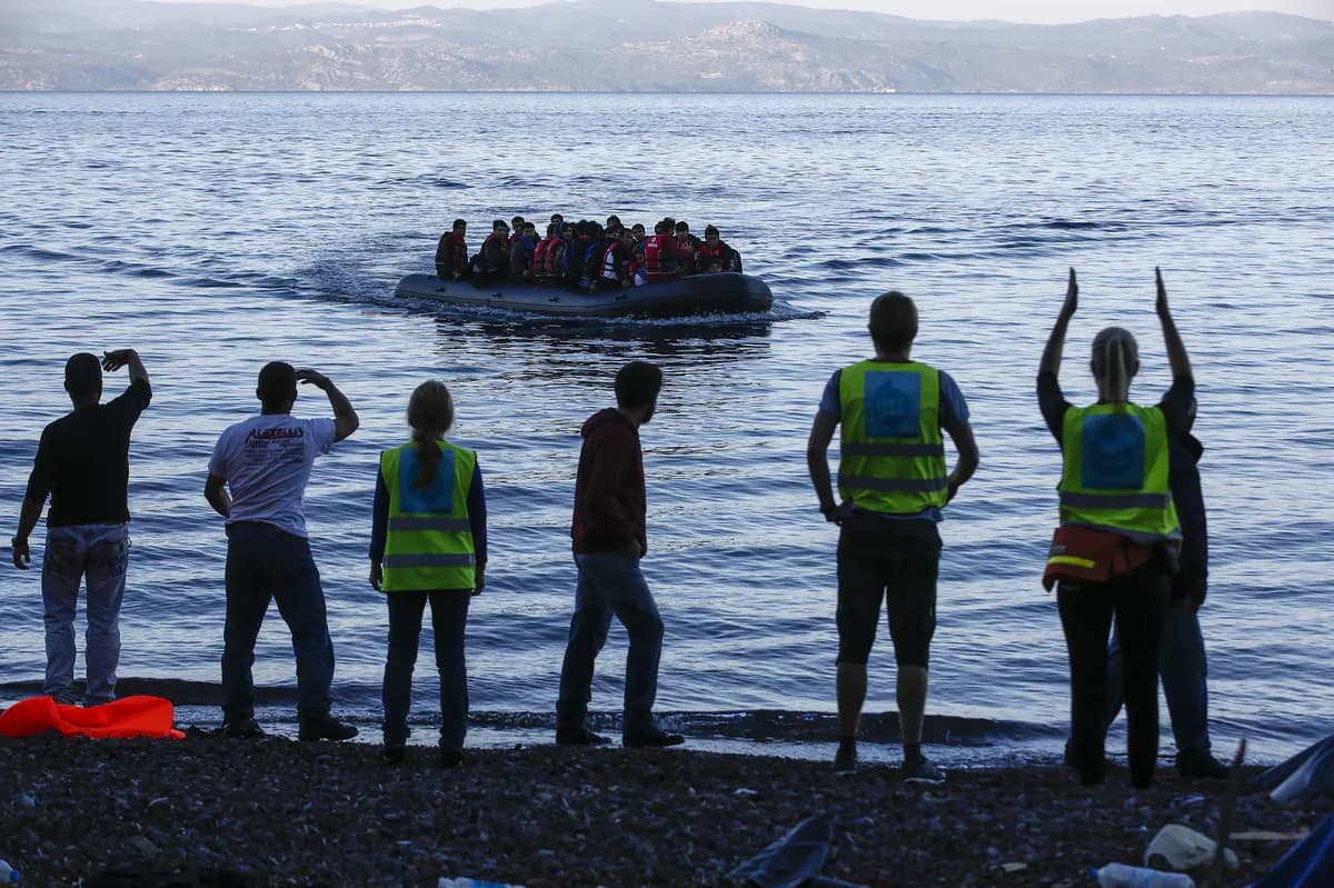 Migranters klättrar ombord på gummibåt medan fransk polis ser på vid Dunkerques