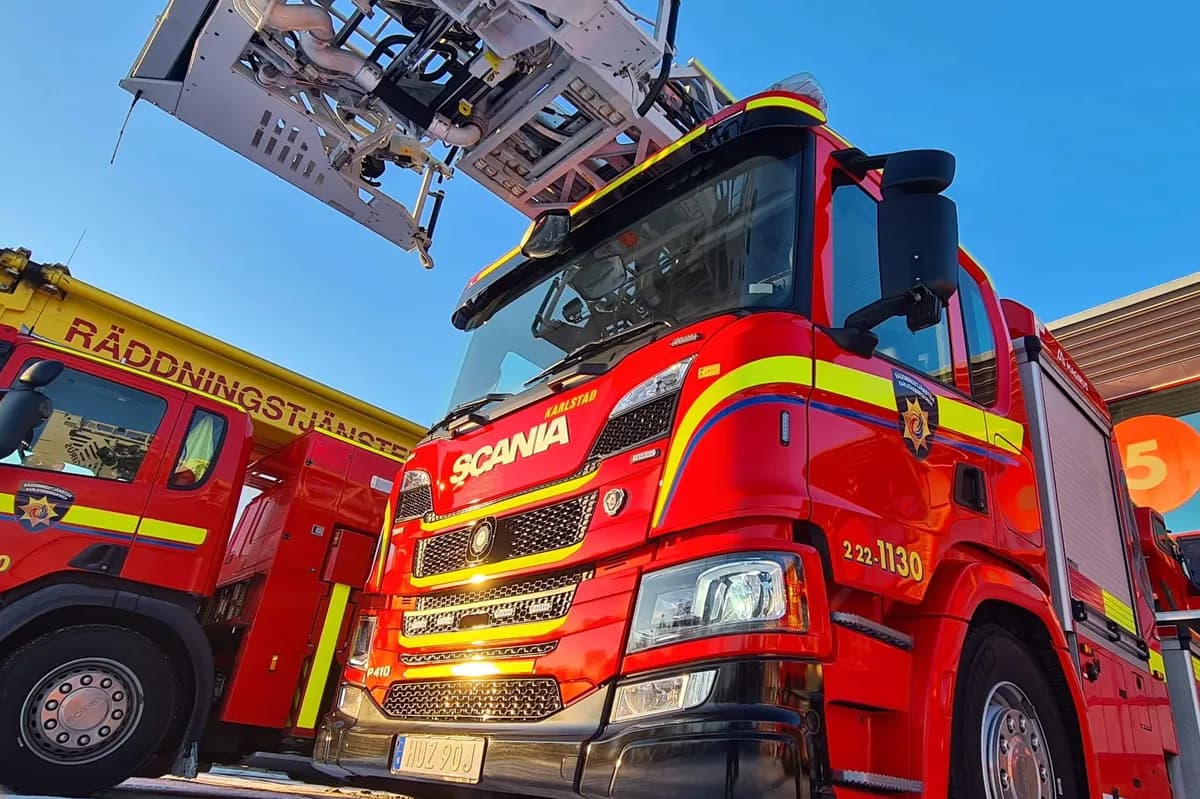 Red Scania aerial ladder truck from below with extended ladder against blue sky